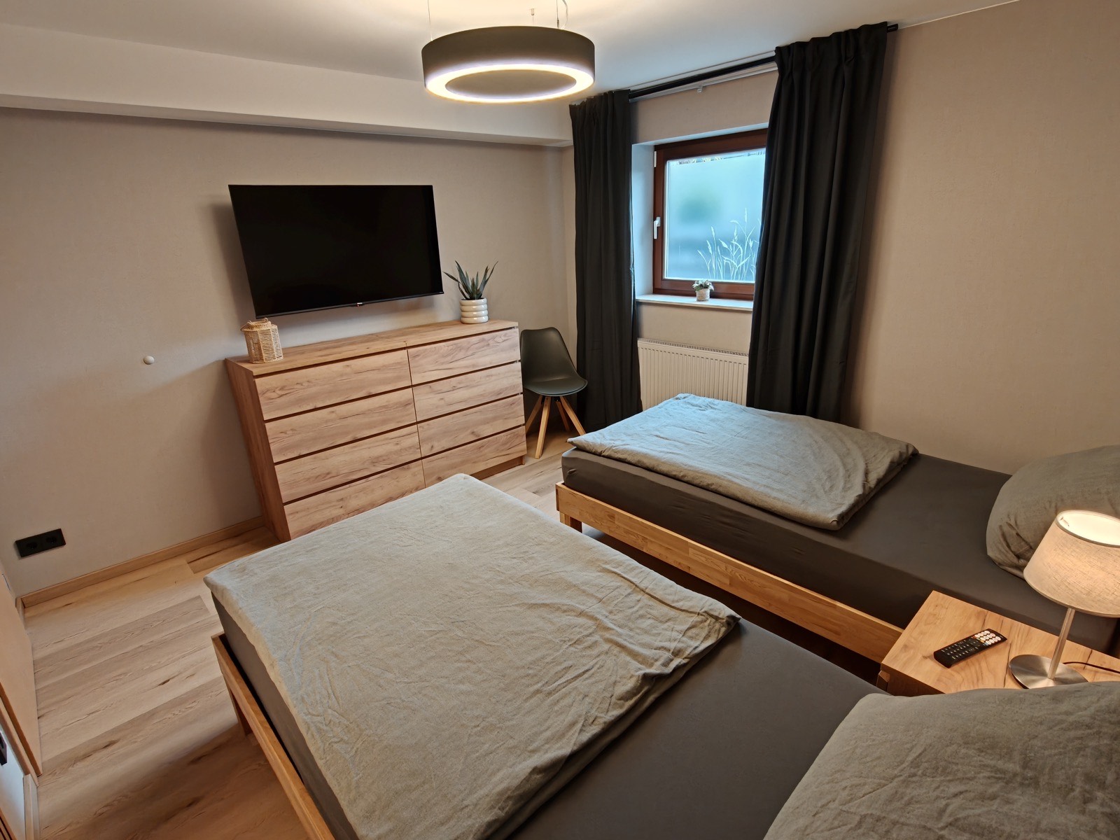 Schlafzimmer mit Kommode, Fernseher und zwei Betten